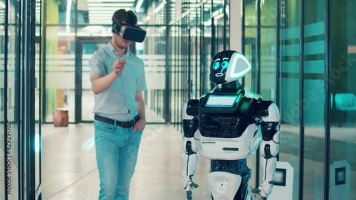 Human and robot communication concept. Businessman is wearing VR-glasses and communicating with a robot photo