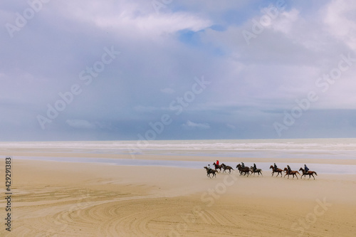 Chevaux montés au galop sur une immense plage de la Baie de Somme
