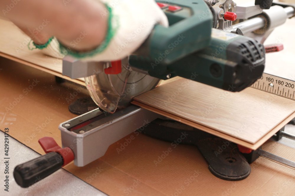 Installation laminate or parquet in the room, worker cuts a laminate of a certain length with an electric saw. self-repair of the floor in the house Installation laminate or parquet in the room, worker cuts a laminate of a certain length with an electric saw. self-repair of the floor in the house