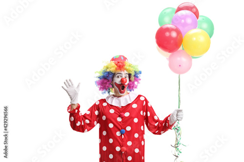 Clown holding a bunch of balloons and waving at camera