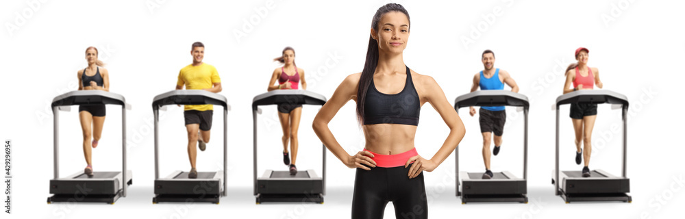 Slim young woman in sportswear posing in front of people running on treadmills Slim young woman in sportswear posing in front of people running on treadmills