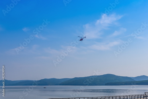 Summer landscape. View of the Angara River and mountains on a sunny summer day. A small helicopter is flying in the sky. Taltsy village, Irkutsk region, Russia. © Eselena