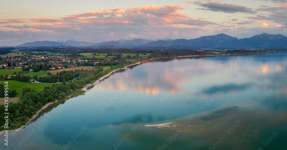 Lake Chiemsee in Bavaria with the Alp mountains during sunset from above, with village Chieming, during summer.