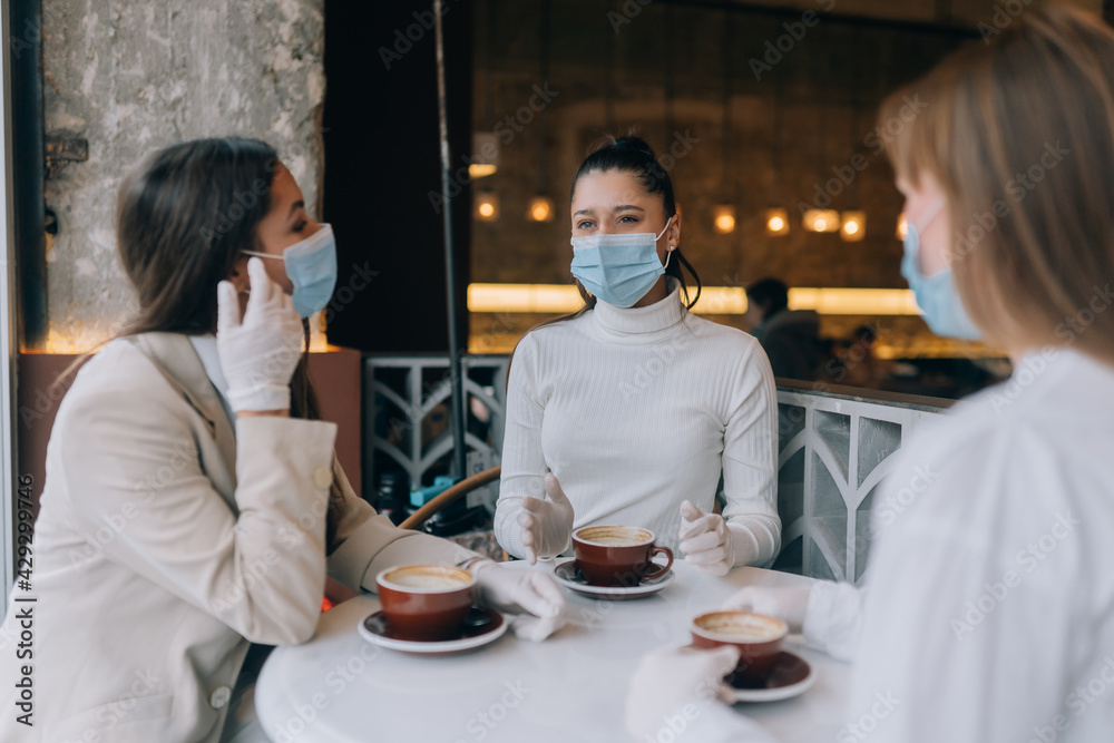 Friends girls met in a cafe. Wear medical protective masks. Friends girls met in a cafe. Wear medical protective masks.