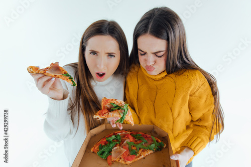 Two sad woman with a slice of pizza on a white background