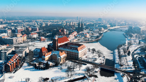 High angle view on winter snowy town  Wroclaw  Poland. Red roofs of sacral buildings and church on sand island. 