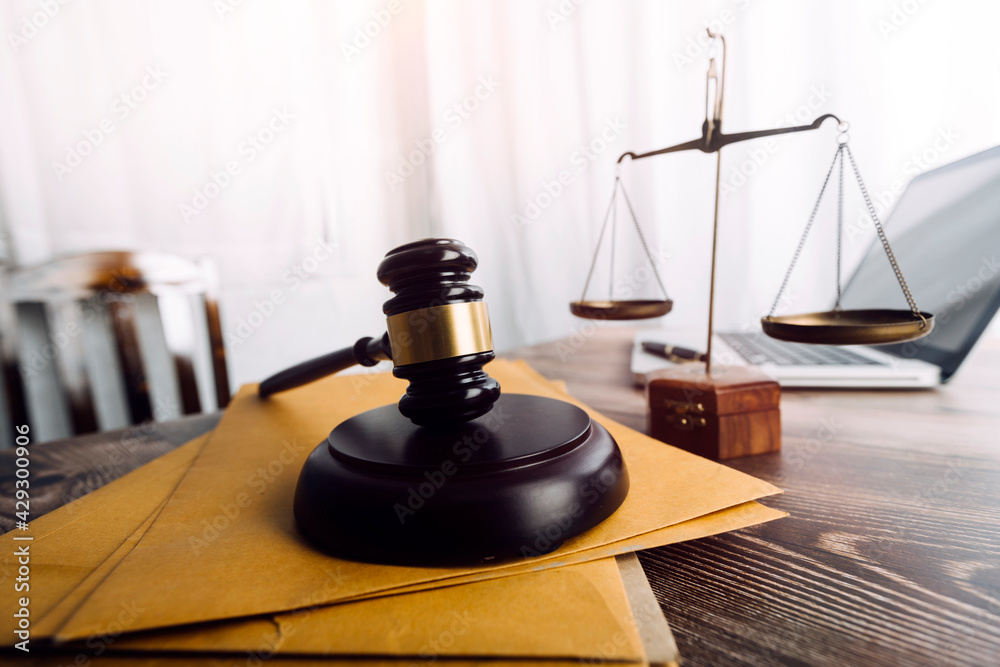 Justice and law concept.Male judge in a courtroom with the gavel, working with, computer and docking keyboard, eyeglasses, on table in morning light Justice and law concept.Male judge in a courtroom with the gavel, working with, computer and docking keyboard, eyeglasses, on table in morning light