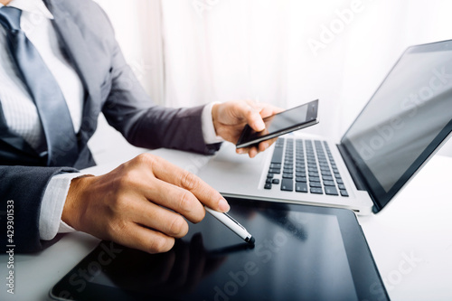 Business people use tablets and hold credit cards as an online shopping concept With a calculator and a book placed on the table © ARMMY PICCA