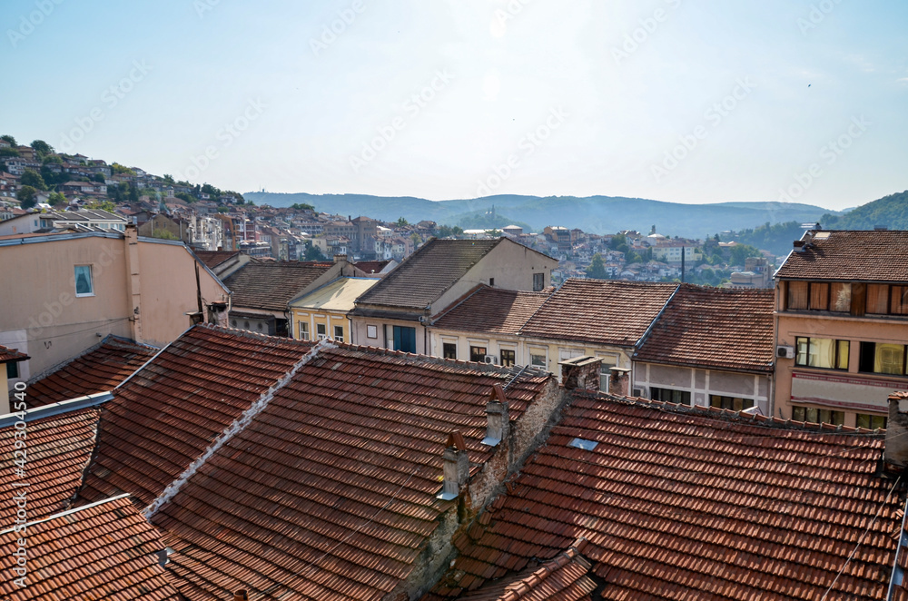 Traditional bulgarian architecture, buildings with red tiled roofs on hills at old town Veliko Tarnovo at sunrise. Bulgaria