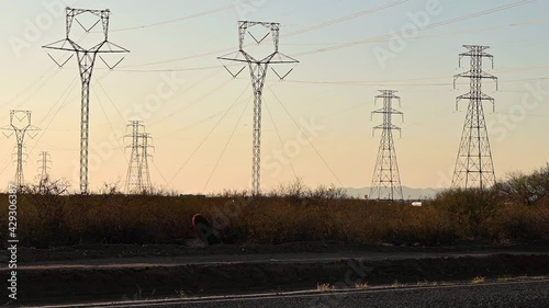 Power lines and pylons. Cars drive by in front of camera. 