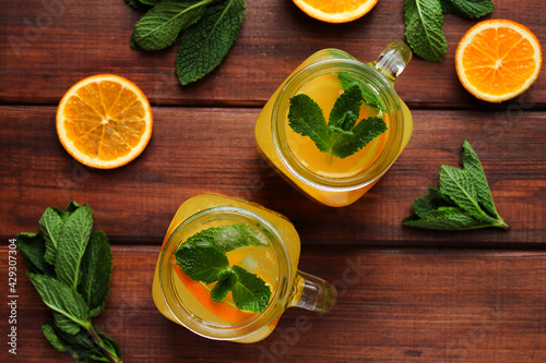 Summer refreshment drinks. Citrus lemonade in jars with ice, mint and oranges on a wooden table. Close-up, selective focus, top view