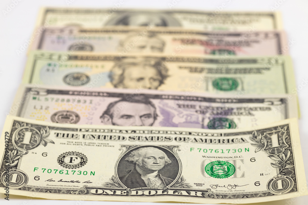 American dollars from one to one hundred lie on a white background. Close-up, selective focus. American dollars from one to one hundred lie on a white background. Close-up, selective focus.