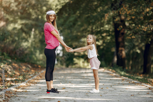 Mother with daughter doing sport in a summer park