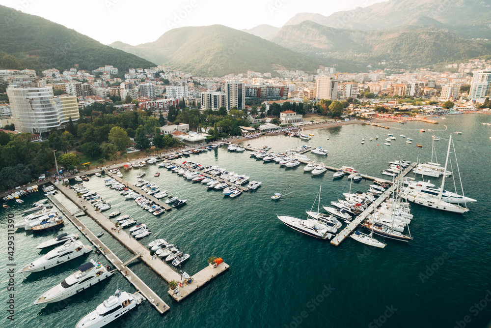 Boat pier with parked yachts against the background of the city of Budva, Montenegro on a bright sunny day