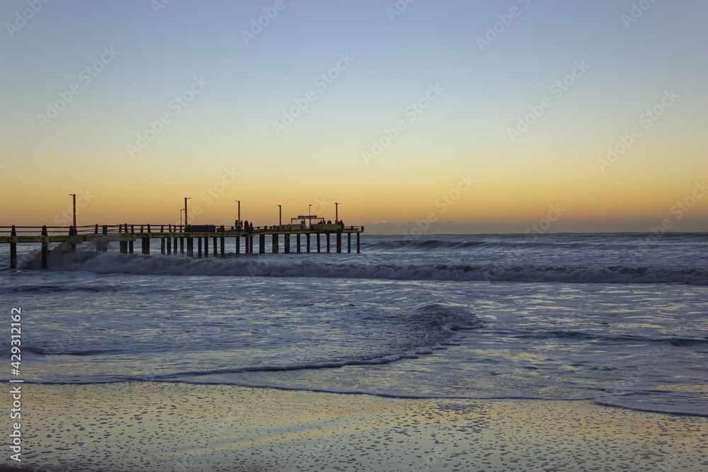 Old pier at sunrise. Beach without people.