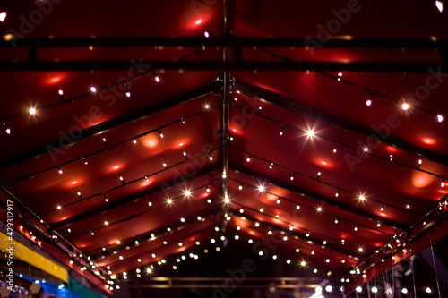 top of the canopy in a red textile gazebo with string light garlands decorative holiday lighting roof terrace night scene. photo