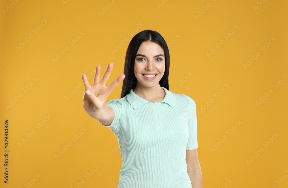 Woman showing number four with her hand on yellow background