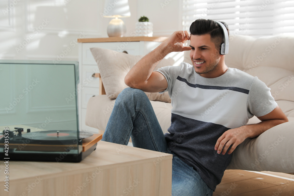 Fototapeta premium Happy man listening to music with turntable at home
