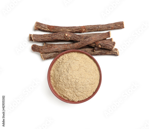 Fototapeta Naklejka Na Ścianę i Meble -  Powder in bowl and dried sticks of liquorice root on white background, top view