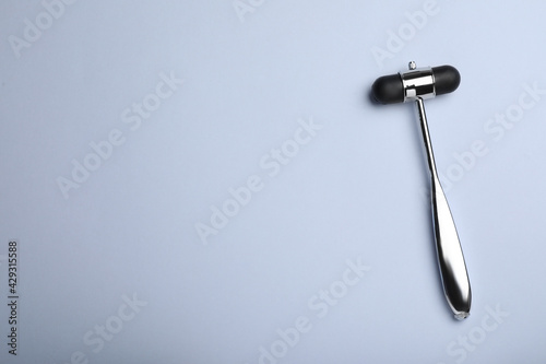 Reflex hammer on grey background, top view with space for text. Nervous system diagnostic