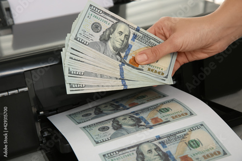 Counterfeiter printing dollar banknotes at table, closeup. Fake money concept photo