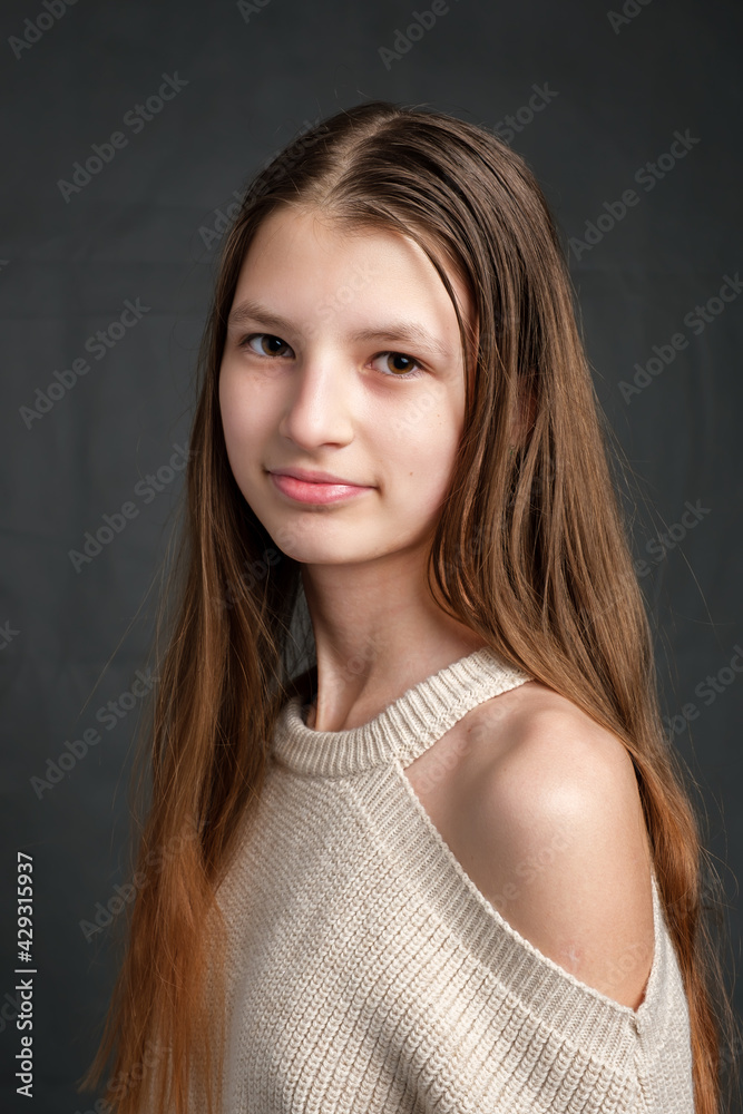 Portrait of beautiful teenager girl smiling and looking at camera on gray background. Vertical orientation Portrait of beautiful teenager girl smiling and looking at camera on gray background. Vertical orientation