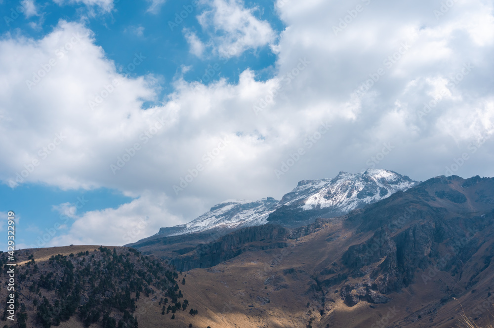 A stunning view of the snow-capped Iztaccihuatl volcanic mountain top in Mexico under a cloudy sky A stunning view of the snow-capped Iztaccihuatl volcanic mountain top in Mexico under a cloudy sky