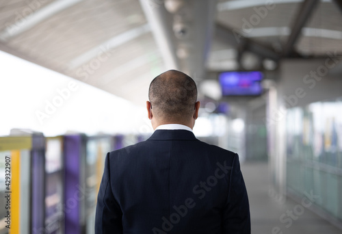 Young asian businessman standing at platform skytrain station. Businessman in urban city travel by sky train.