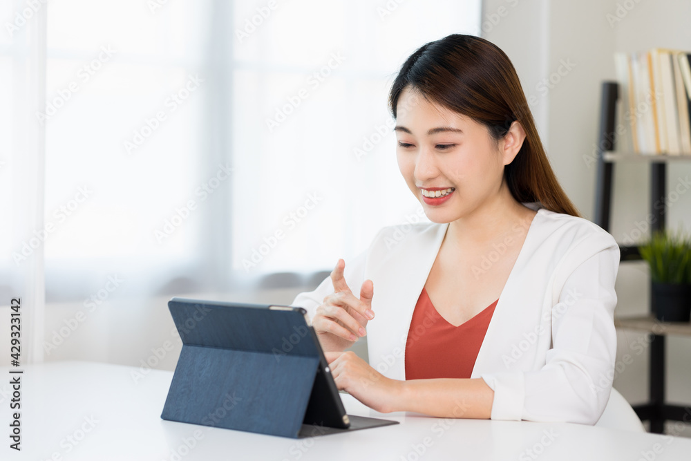 Young asian beautiful business woman working with tablet sitting at home. Smiling charming happy young female doing homework meeting conference with team at home. Young asian beautiful business woman working with tablet sitting at home. Smiling charming happy young female doing homework meeting conference with team at home.