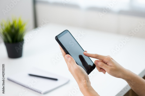 Close up business woman hands using smartphone. Young female texting touching on display of cell phone.