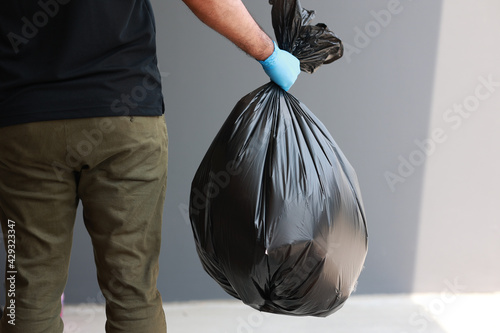 Obraz na plátně The young man separated the dangerous waste into a large black bag and put it in the trash