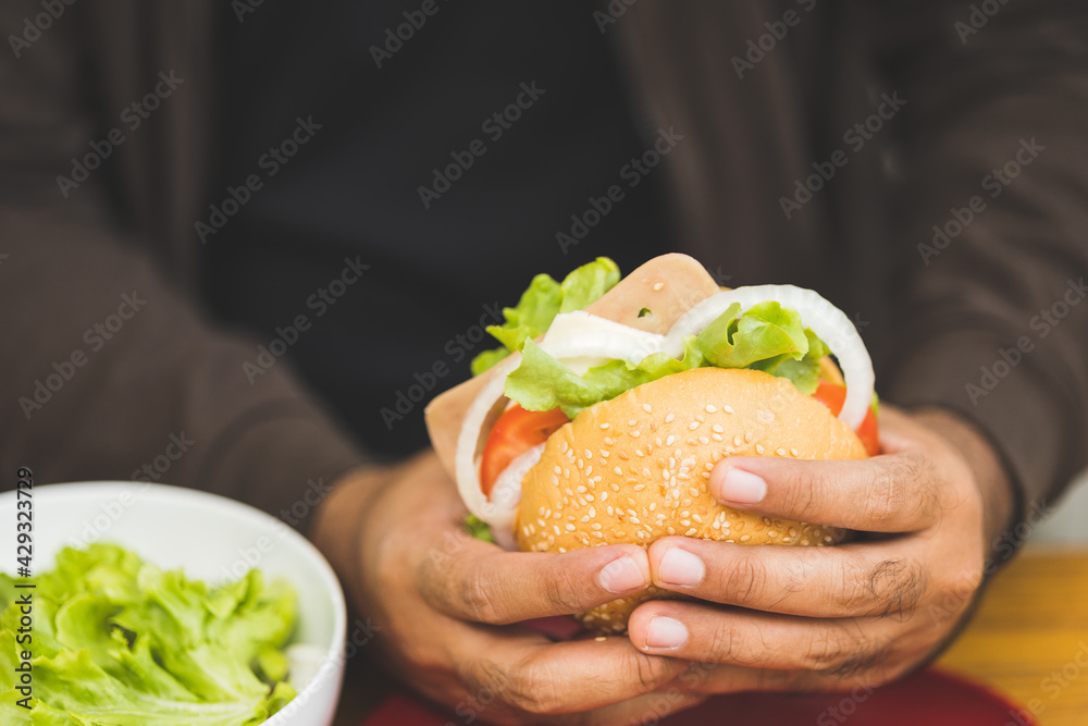 Man eating breakfast Hamburger buns stuffed with vegetables and meat and tomatoes Healthy breakfast It has good carbohydrates and vitamins. Fast food to eat in the morning before going to work