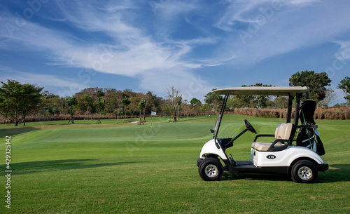 Golf cart on golf course, parking on fairway. Equipment and golf club bag are put in ready for golfer to player in field with sunlight rays background