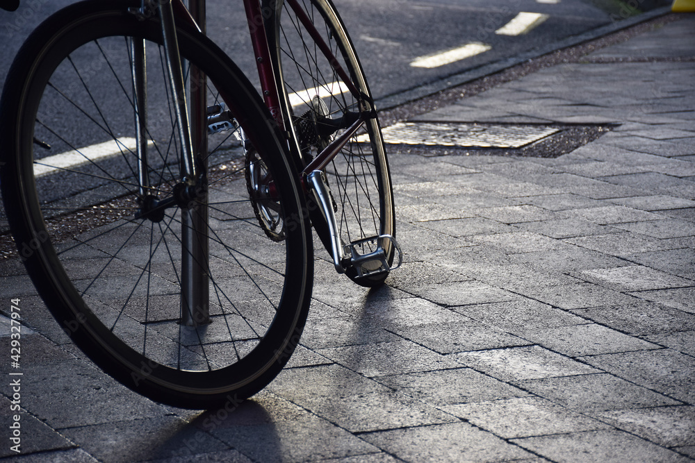 A bicycle leans against a pole on an urban pavement A bicycle leans against a pole on an urban pavement