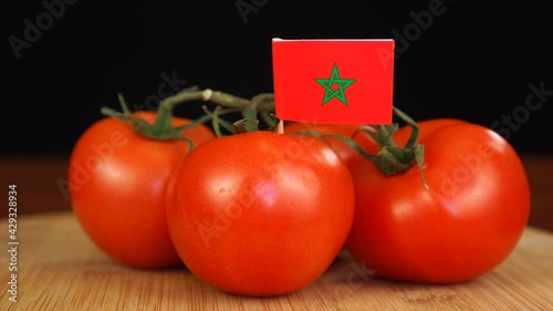 Man placing decorative toothpick with flag of Moroko into bunch of tomatoes. photo