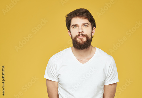 Brunette man on a yellow background in a white t-shirt cropped view