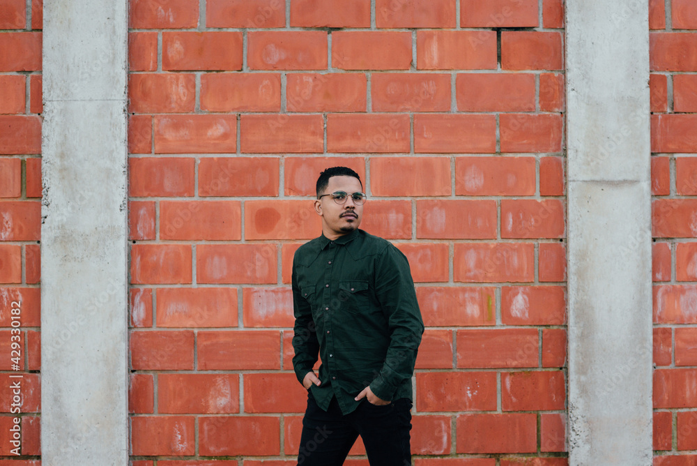 portrait of male model with green military t-shirt on brick wall portrait of male model with green military t-shirt on brick wall