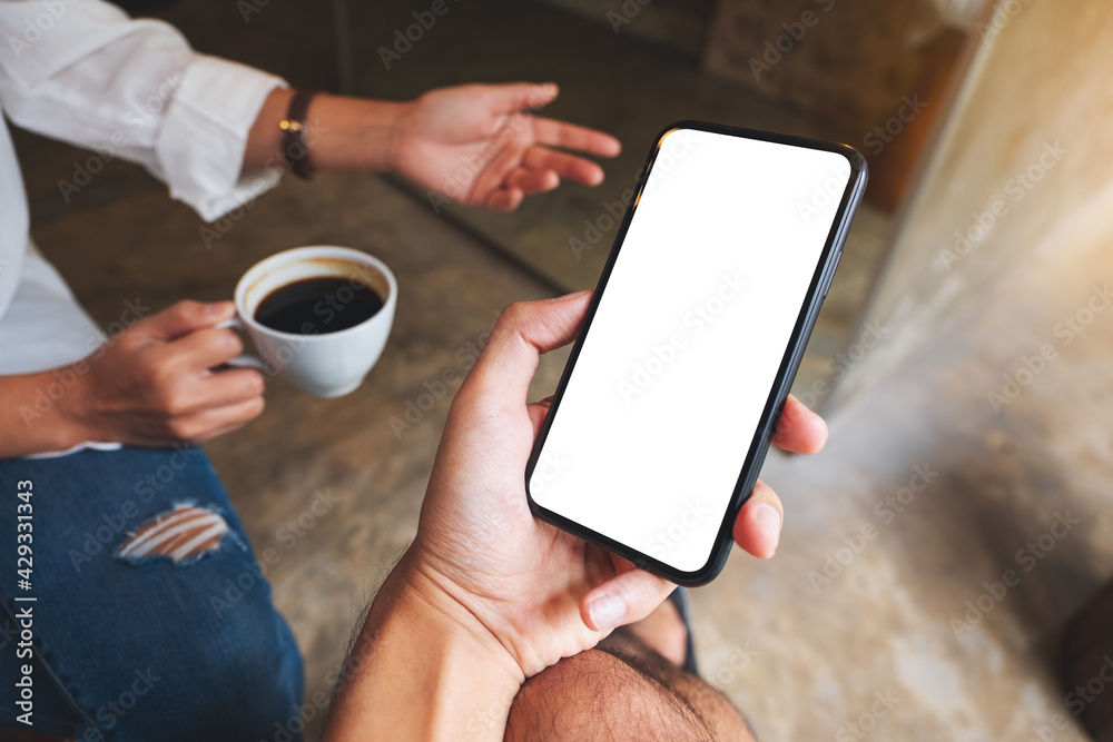 Mockup image of a man holding and showing mobile phone with blank desktop screen to his friend while having conversation together Mockup image of a man holding and showing mobile phone with blank desktop screen to his friend while having conversation together
