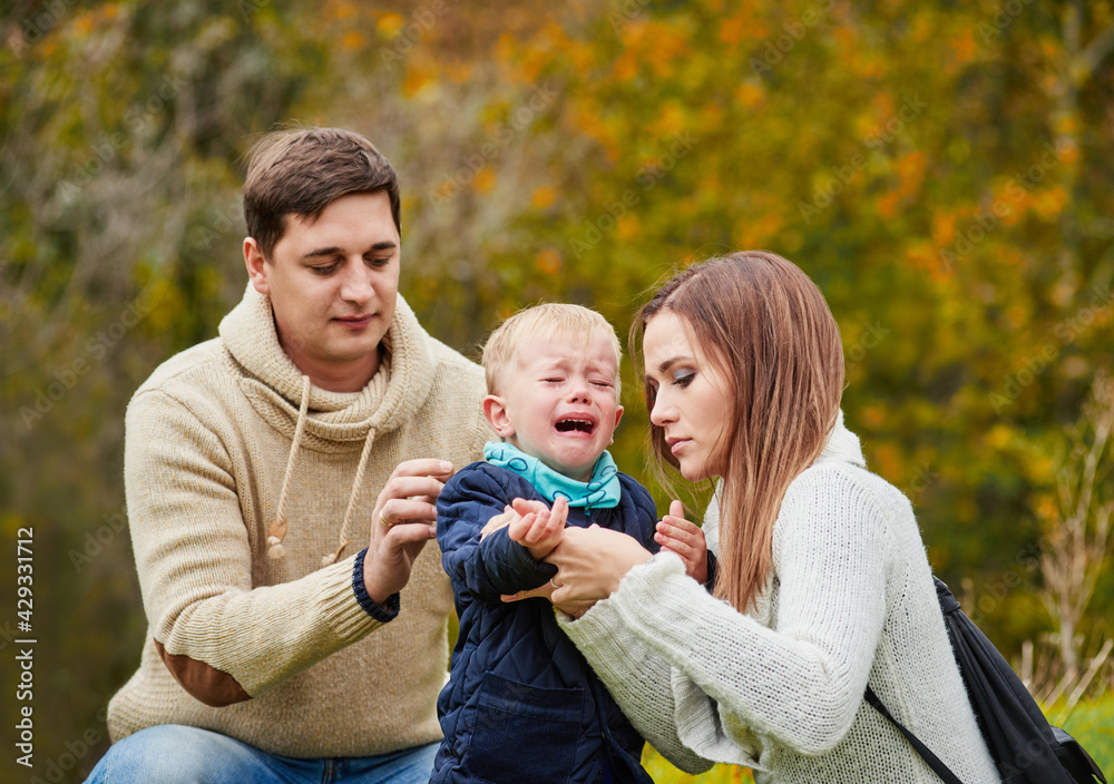 Little boy crying during walk with parents in park. Child's mood swings concept Little boy crying during walk with parents in park. Child's mood swings concept