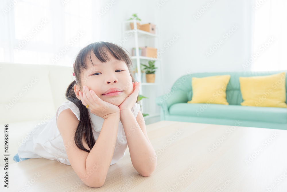 Little asian girl sitting alone in living room and looking at camera with boring face. Little asian girl sitting alone in living room and looking at camera with boring face.