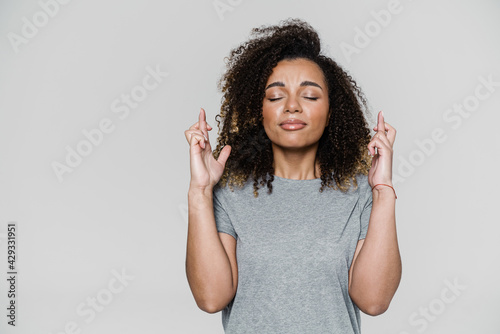 The curly-haired woman with closed eyes and crossing fingers standing in the studio
