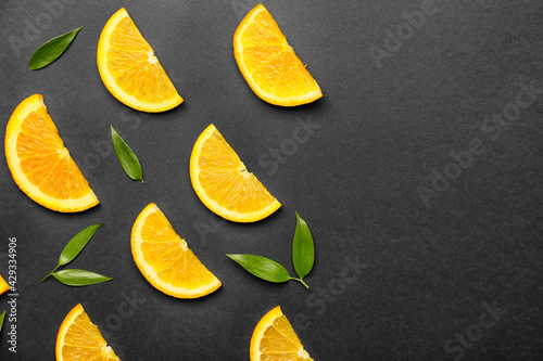 Slices of fresh oranges with green leaves on dark background