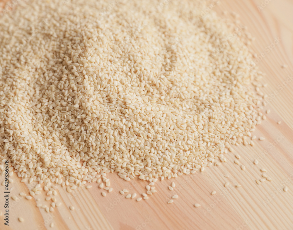 Heap of peeled sesame seeds on a wooden table close-up. Food concept.. Heap of peeled sesame seeds on a wooden table close-up. Food concept..