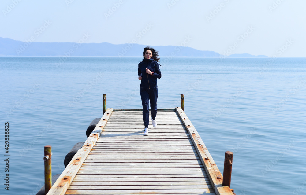45 y.o. Russian woman running on a wooden pier by the Japanese sea