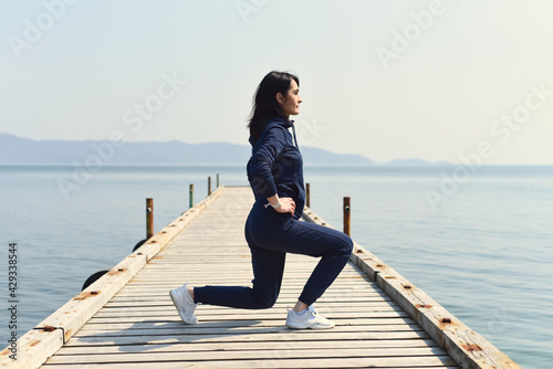 45 y.o. Russian woman squatting on a wooden pier by the Japanese sea