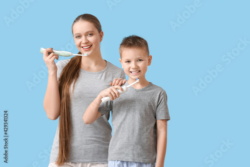 Mother and little son brushing teeth on color background
