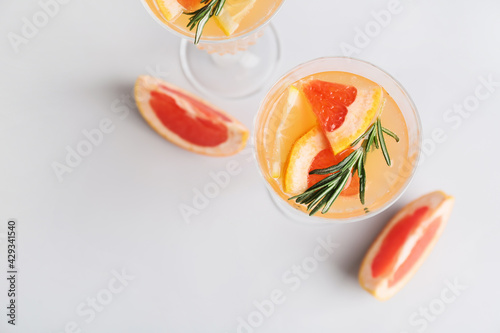 Glasses of tasty grapefruit cocktail with rosemary on grey background