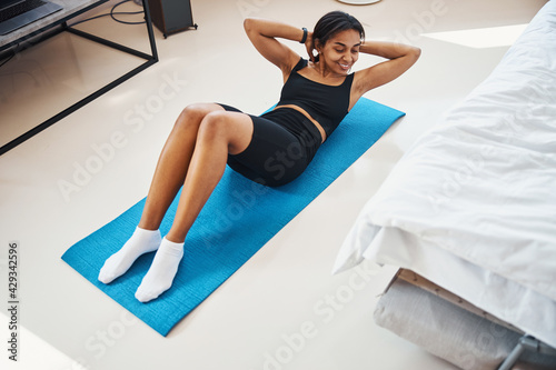Cheerful young woman doing exercise for abs at home