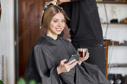 Confident male stylist is dyeing hair of blond caucasian female client