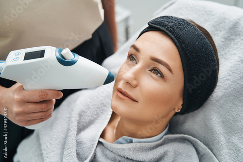 Papier peint Cosmetician performing a face-lifting procedure with a CO2 mesotherapy gun